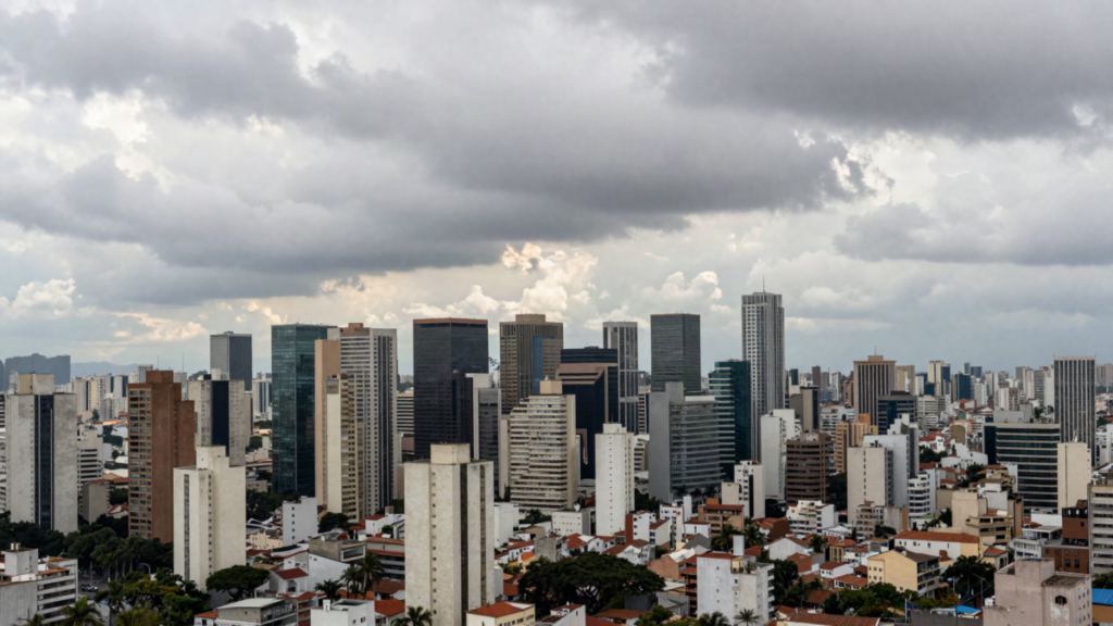 Skyline de metropole brasileira sob ceu variavel entre sol e nuvens