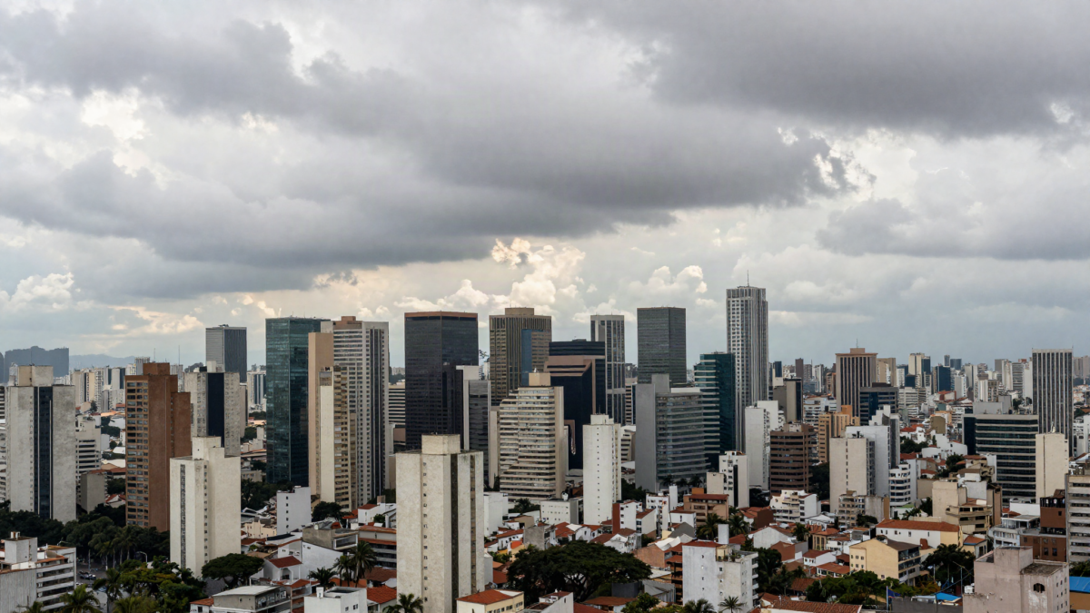 Skyline de metropole brasileira sob ceu variavel entre sol e nuvens