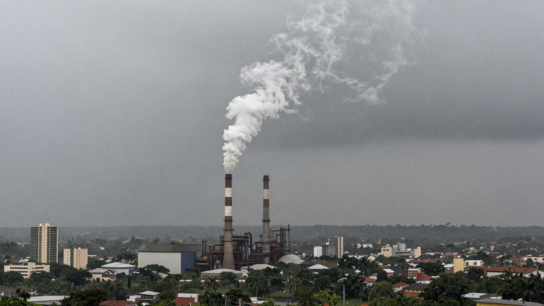 Chamines industriais liberando fumaca em ceu cinzento com chuva de poluicao
